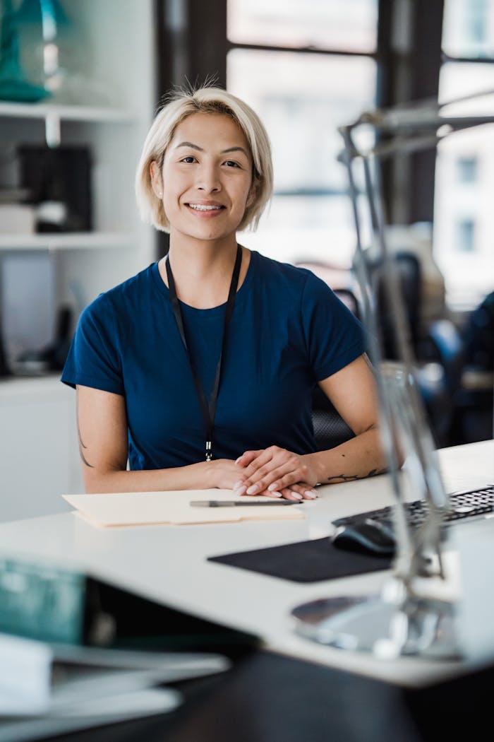 Confident woman smiling while sitting at an office desk, conveying a positive work environment.