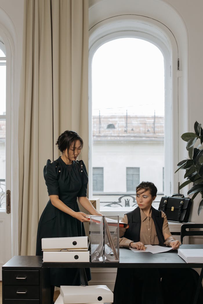 Two women working together with documents in a stylish office setting.