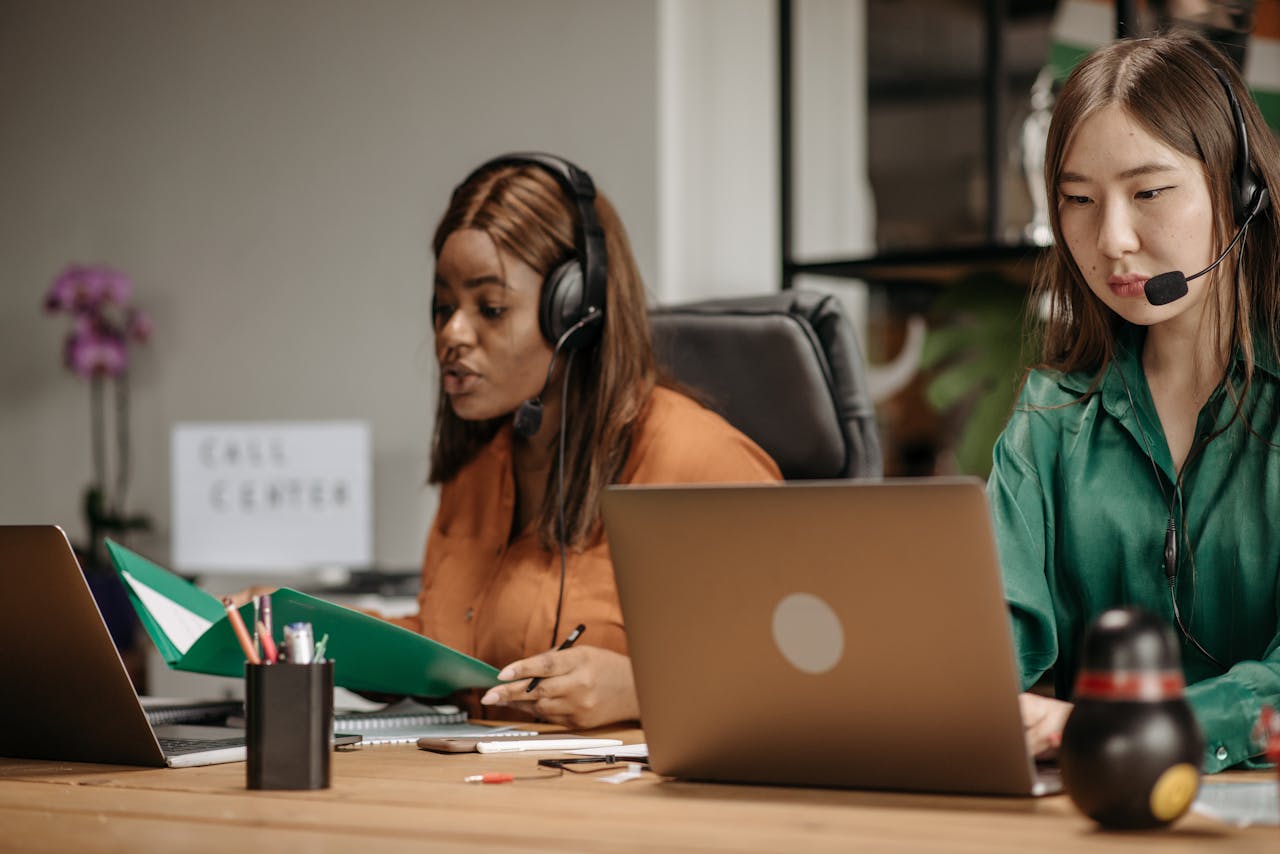 Two call center agents collaborating with laptops in a modern office.